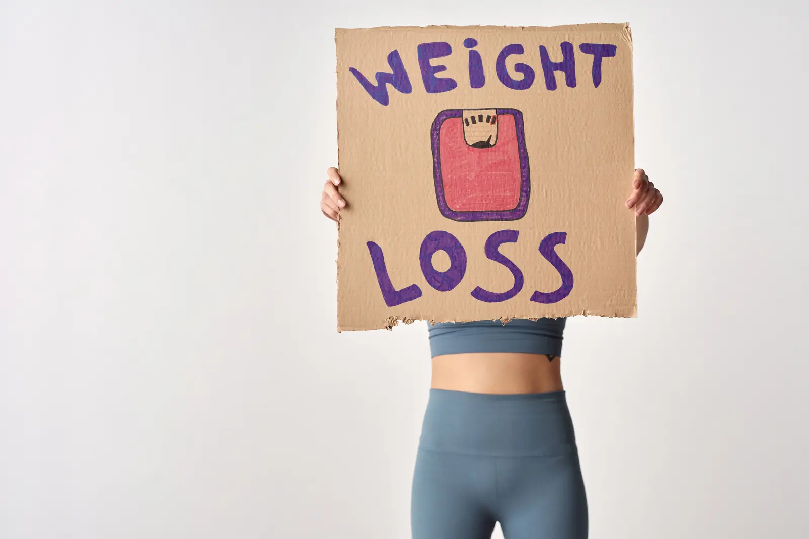 Holding a hand-drawn weight loss sign